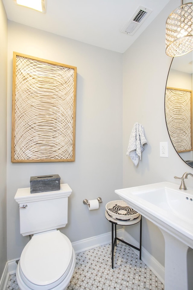 bathroom featuring toilet, a sink, visible vents, and baseboards