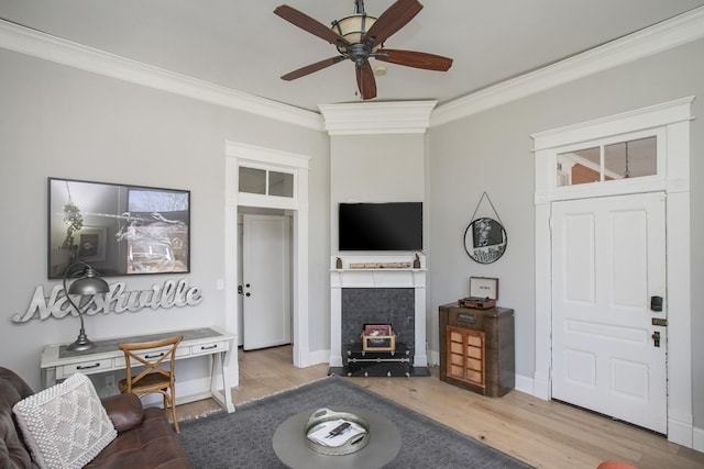 living area featuring ceiling fan, baseboards, crown molding, and wood finished floors