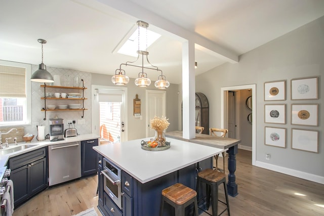 kitchen featuring a breakfast bar area, stainless steel appliances, a sink, blue cabinetry, and open shelves