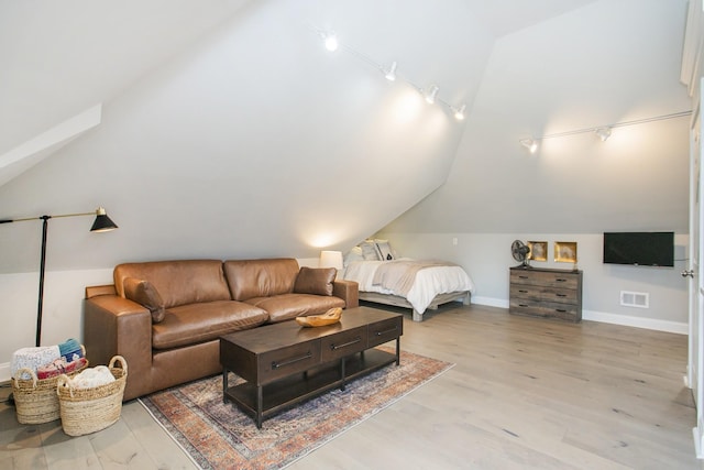 bedroom with lofted ceiling, visible vents, light wood-style floors, track lighting, and baseboards