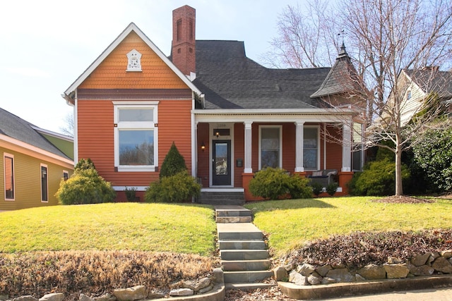 victorian home with a shingled roof, a chimney, a front lawn, and a porch