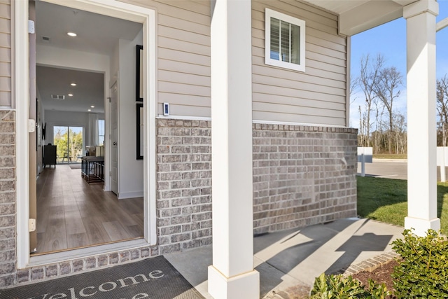 doorway to property with visible vents and brick siding