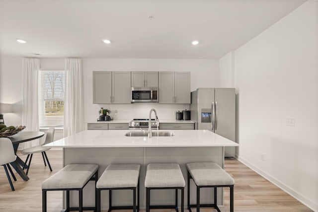 kitchen with stainless steel appliances, a breakfast bar, backsplash, and gray cabinetry