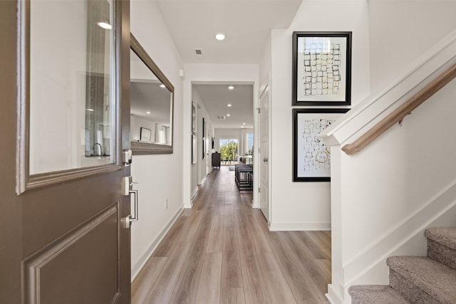 hallway with recessed lighting, visible vents, light wood-style flooring, baseboards, and stairs