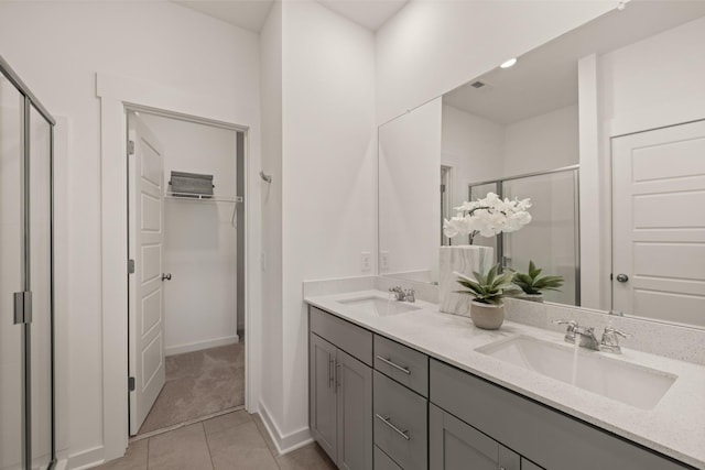 bathroom featuring tile patterned floors, a sink, a walk in closet, and a shower stall