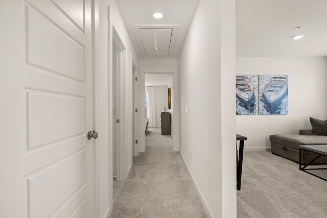 hallway featuring recessed lighting, attic access, baseboards, and light colored carpet