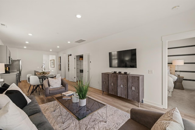 living room featuring visible vents, baseboards, light wood-style flooring, and recessed lighting