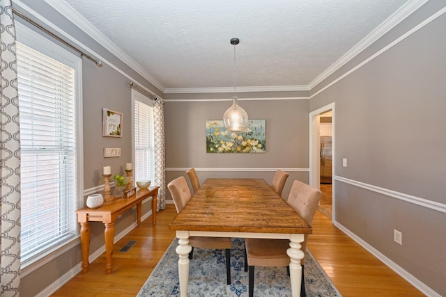 dining area featuring visible vents, plenty of natural light, light wood-style flooring, and a textured ceiling