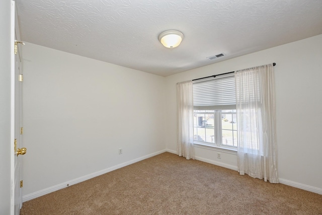 empty room featuring baseboards, a textured ceiling, visible vents, and light colored carpet