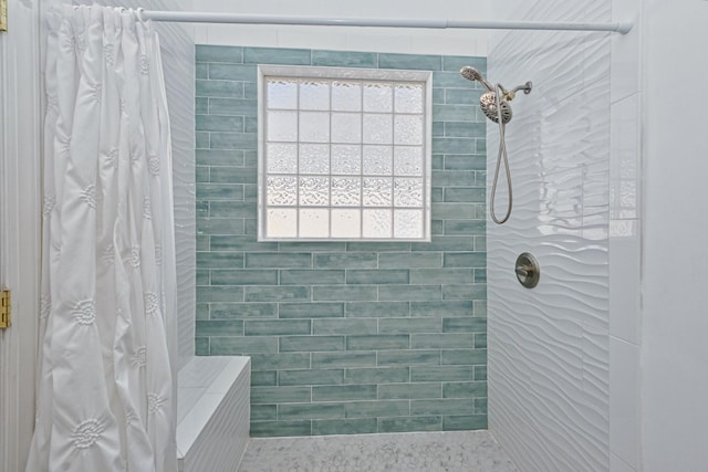 bathroom featuring a tile shower and a healthy amount of sunlight