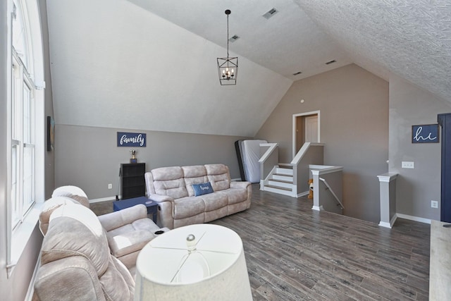 living area featuring lofted ceiling, a textured ceiling, wood finished floors, visible vents, and baseboards