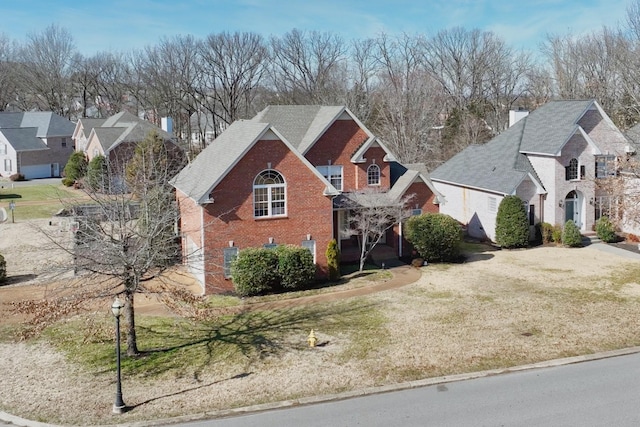 traditional-style house featuring brick siding, a front lawn, and a residential view