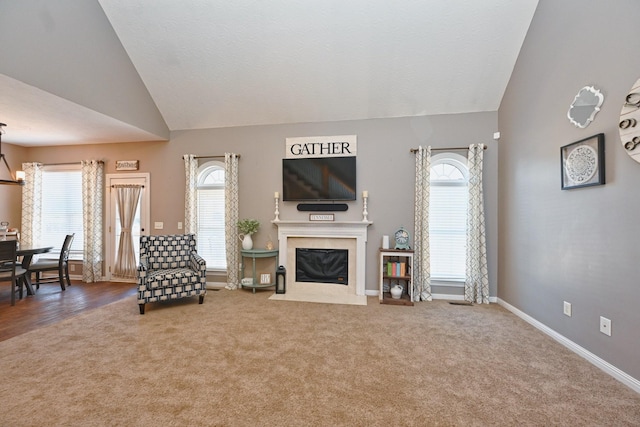 carpeted living area featuring high vaulted ceiling, a fireplace, and baseboards