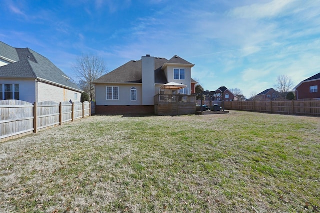 back of property with a fenced backyard, crawl space, a lawn, a wooden deck, and a chimney