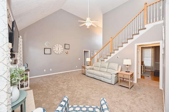 carpeted living area with stairs, ceiling fan, high vaulted ceiling, and baseboards