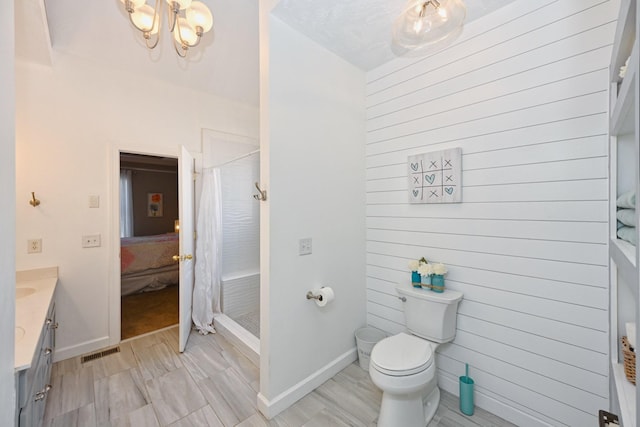 full bath with toilet, visible vents, vanity, baseboards, and a stall shower