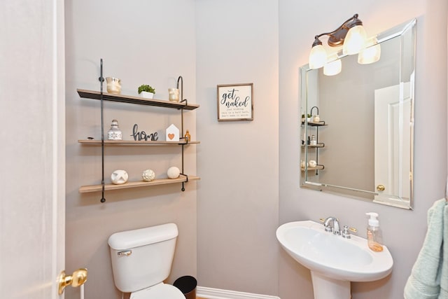 half bathroom with a sink, toilet, and baseboards