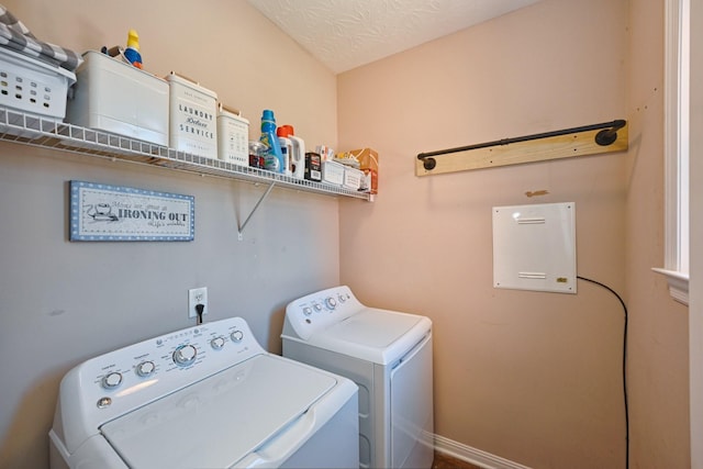 clothes washing area with laundry area, baseboards, a textured ceiling, and washing machine and clothes dryer