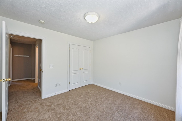 unfurnished bedroom with a closet, carpet flooring, a textured ceiling, and baseboards