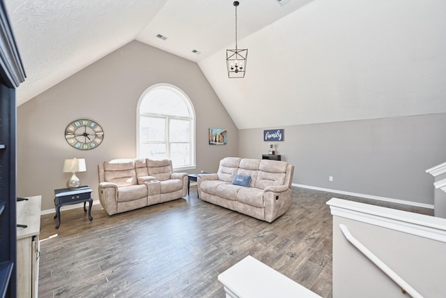 living area with visible vents, vaulted ceiling, baseboards, and wood finished floors