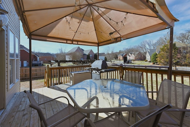 deck with outdoor dining area, grilling area, a gazebo, fence, and a residential view