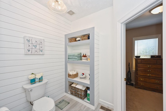 bathroom with toilet, visible vents, and a textured ceiling