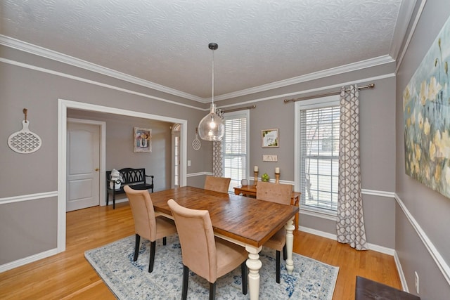 dining room featuring crown molding, light wood-style flooring, baseboards, and a textured ceiling