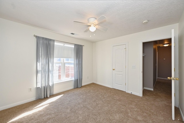 unfurnished bedroom featuring carpet, visible vents, a ceiling fan, a textured ceiling, and baseboards