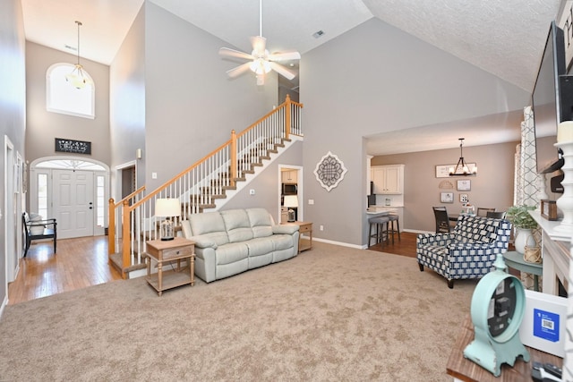 living room with plenty of natural light, stairway, carpet flooring, and ceiling fan with notable chandelier