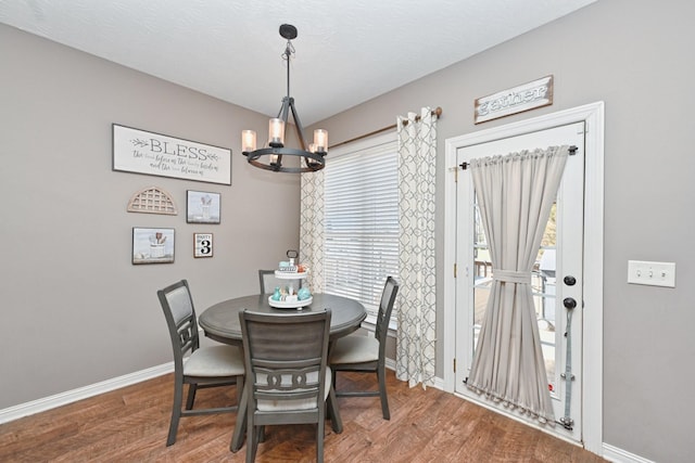 dining room with a textured ceiling, baseboards, a chandelier, and wood finished floors