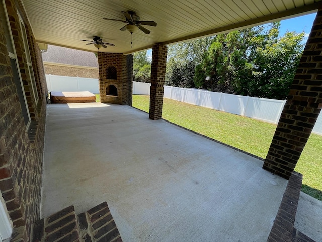 view of patio with a fenced backyard, ceiling fan, and a fireplace