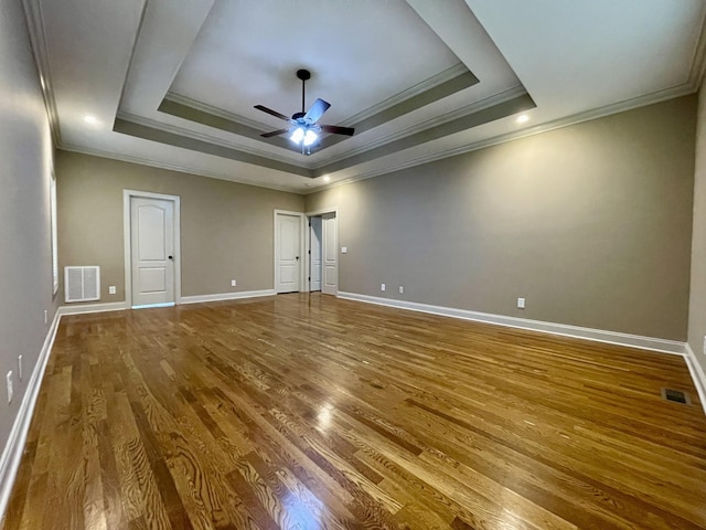 empty room featuring a raised ceiling, visible vents, and wood finished floors