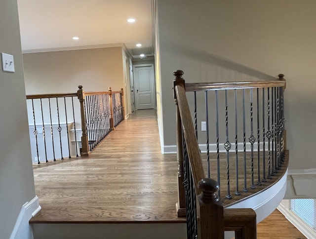 hallway featuring recessed lighting, ornamental molding, an upstairs landing, wood finished floors, and baseboards