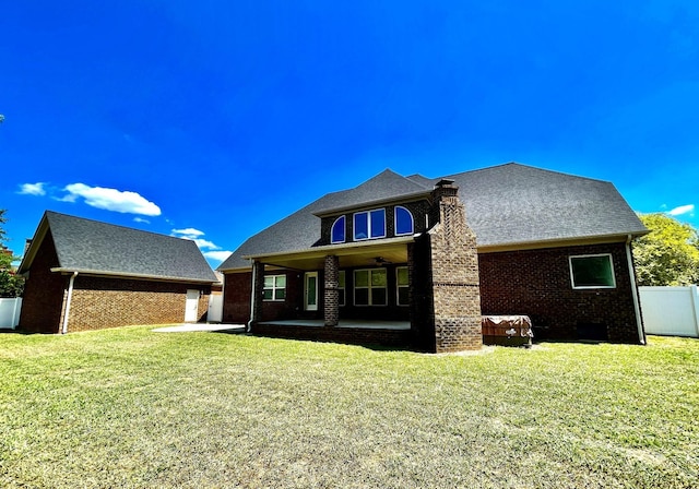 back of property featuring brick siding, a lawn, fence, and a patio