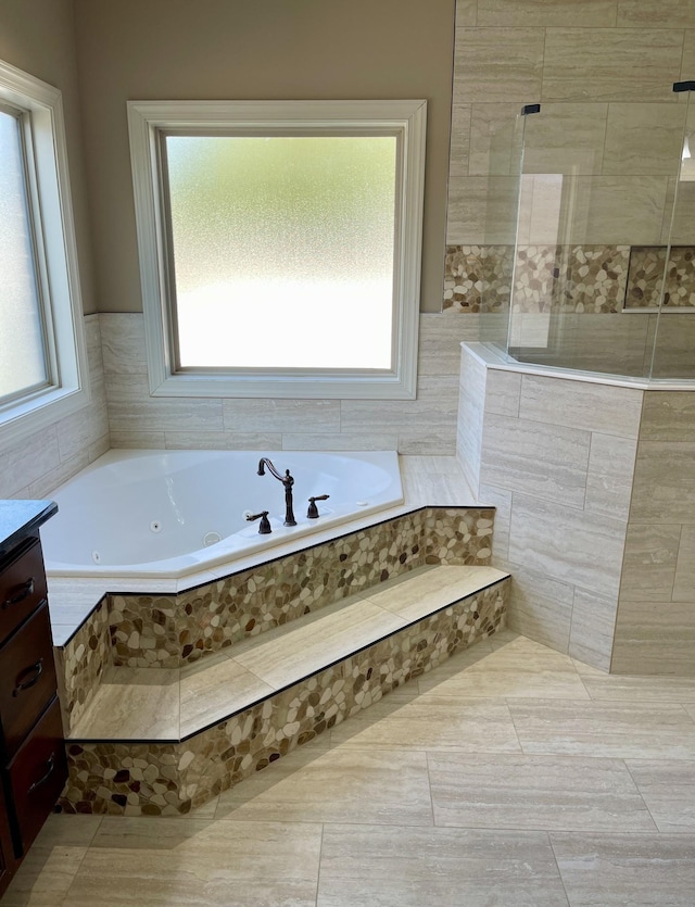 bathroom with a tub with jets, a walk in shower, and vanity