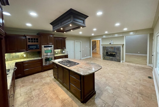 kitchen with appliances with stainless steel finishes, recessed lighting, a tile fireplace, and decorative backsplash