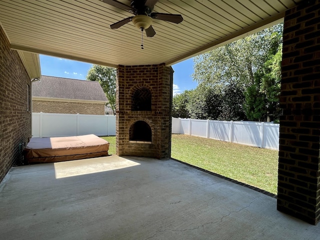 view of patio featuring an outdoor brick fireplace, a fenced backyard, and a ceiling fan