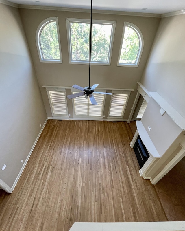 unfurnished living room featuring baseboards, a glass covered fireplace, wood finished floors, and a healthy amount of sunlight