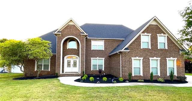 view of front of property with brick siding, a front yard, and french doors