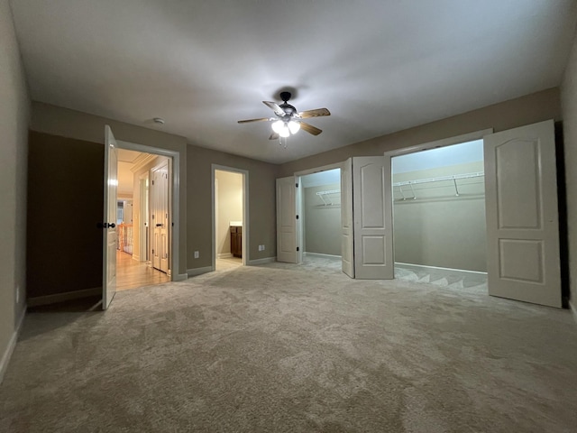 unfurnished bedroom with light carpet, ensuite bath, ceiling fan, and baseboards