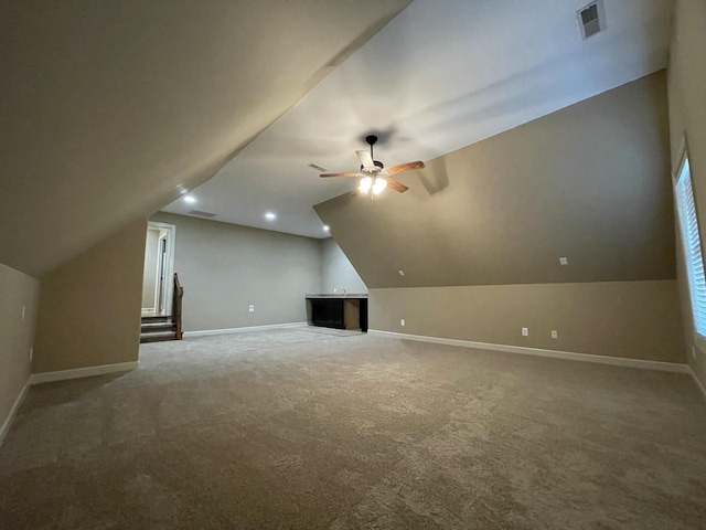 additional living space with carpet, lofted ceiling, visible vents, a ceiling fan, and baseboards