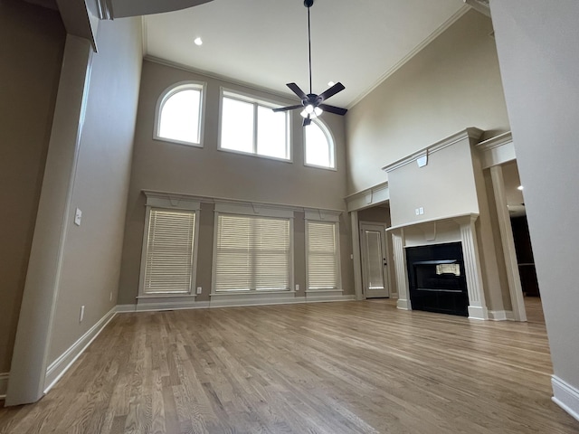 unfurnished living room featuring ceiling fan, baseboards, wood finished floors, and a multi sided fireplace