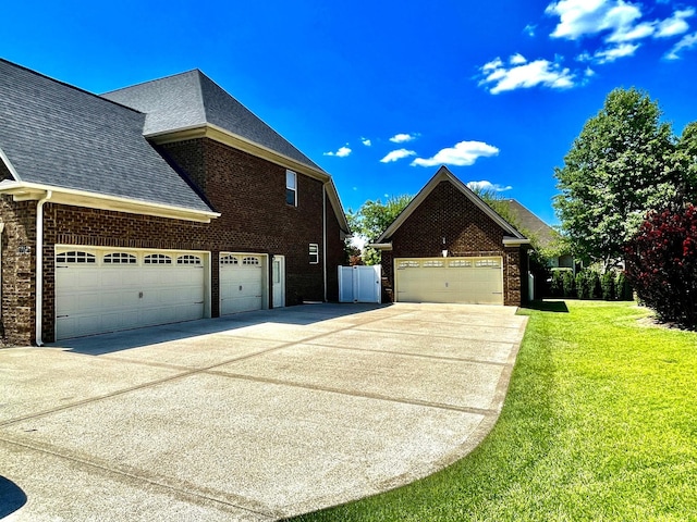 view of property exterior featuring driveway, brick siding, and a lawn