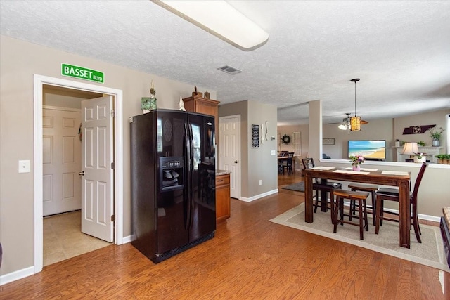 kitchen with light wood-style floors, a textured ceiling, visible vents, and black fridge