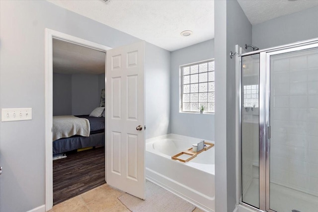 bathroom with ensuite bathroom, a shower stall, a textured ceiling, a bath, and tile patterned floors