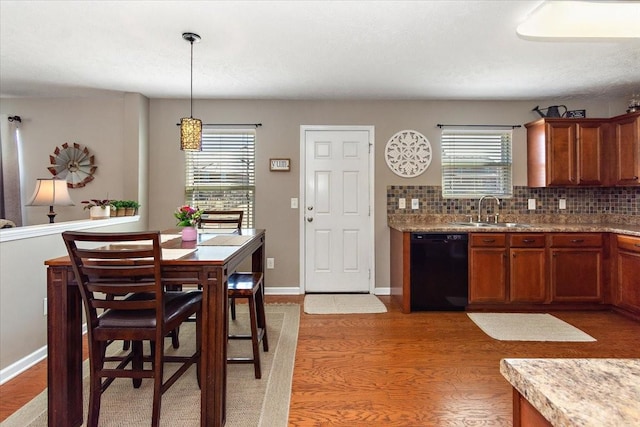 kitchen with brown cabinets, tasteful backsplash, light wood-style floors, a sink, and dishwasher