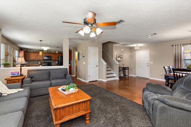 living area featuring visible vents, stairway, ceiling fan, a textured ceiling, and baseboards