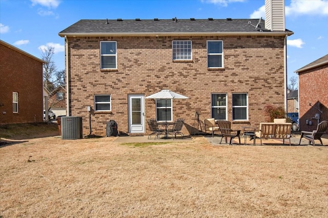 back of property featuring a patio, a chimney, a yard, central AC, and brick siding