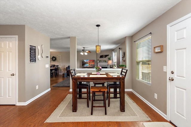 dining area with a ceiling fan, a textured ceiling, baseboards, and wood finished floors