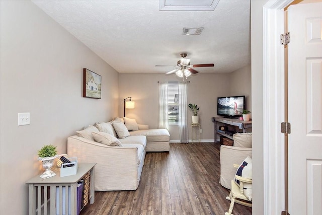 living area with baseboards, visible vents, a ceiling fan, dark wood-type flooring, and a textured ceiling